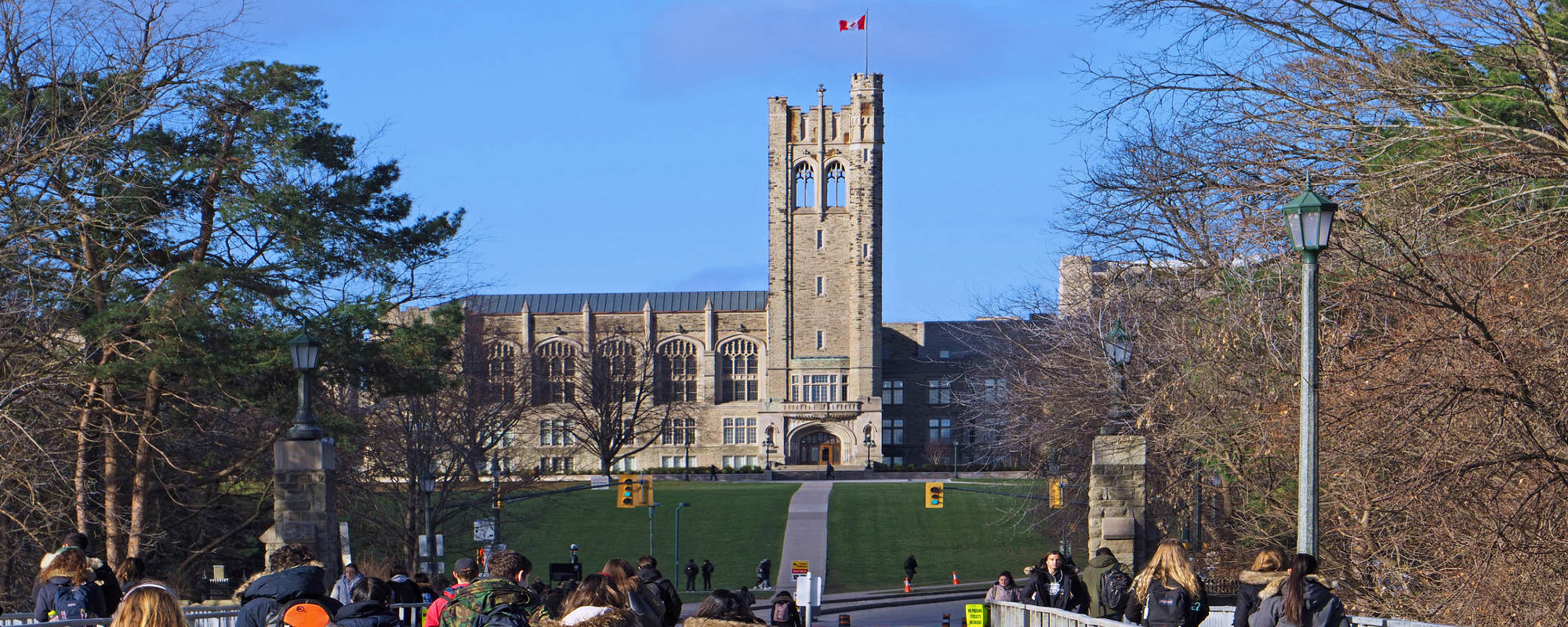 Canadian colleges themed stock - university students at University of Western Ontario walking towards University College building in the horizon.